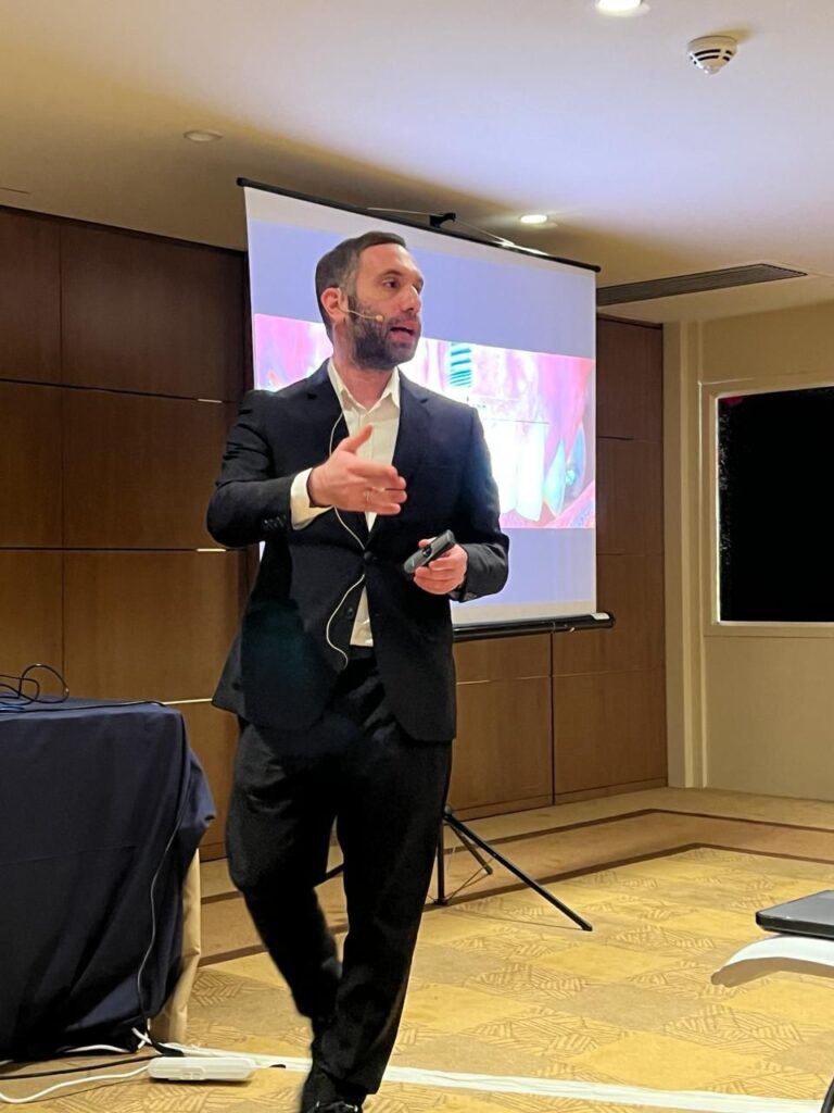 Man presenting in conference room with projector screen.