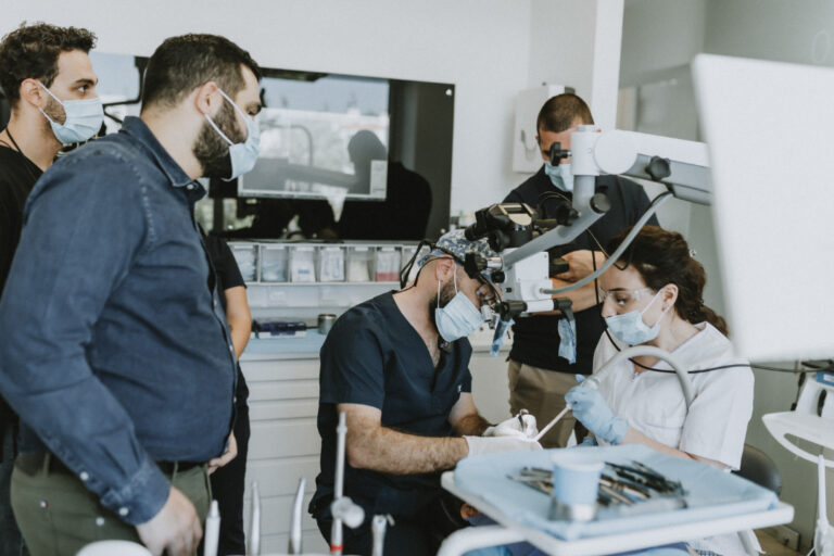 Dentists performing oral surgery with assistants observing.